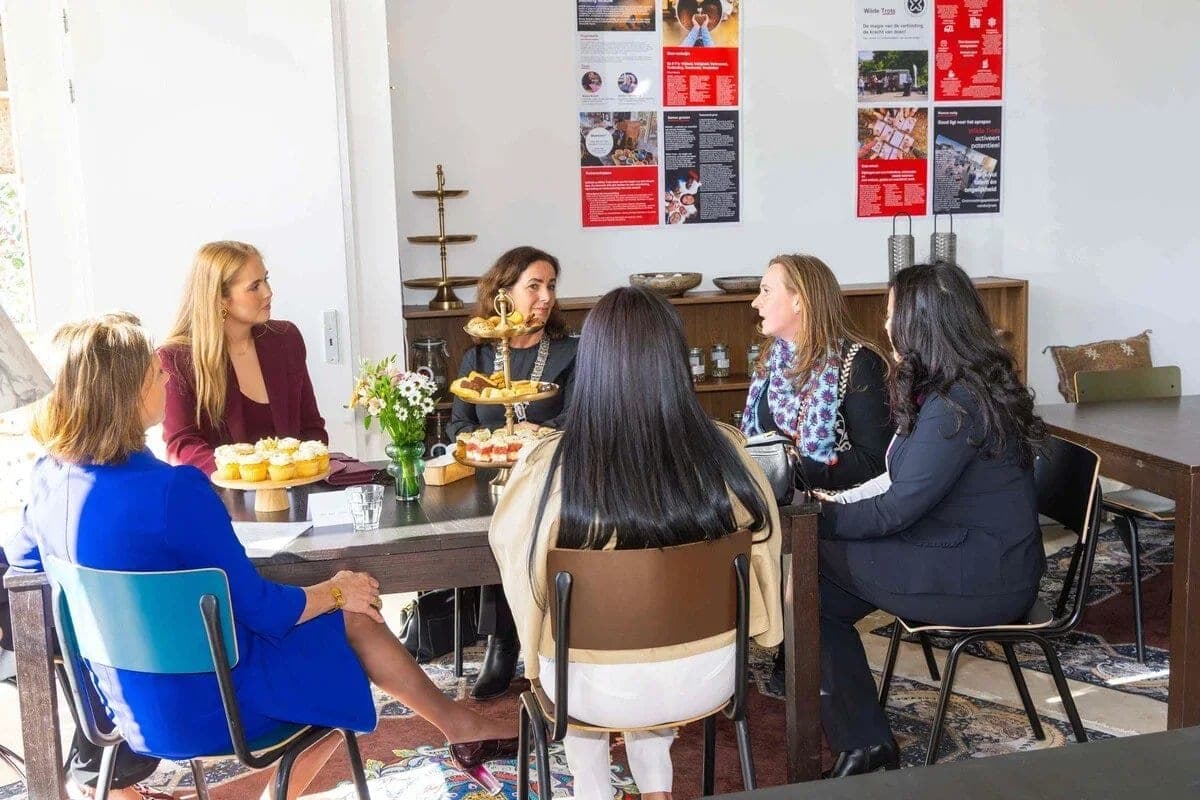 Een gesprek aan een tafel met cupcakes en bloemen tijdens het werkbezoek van prinses Amalia